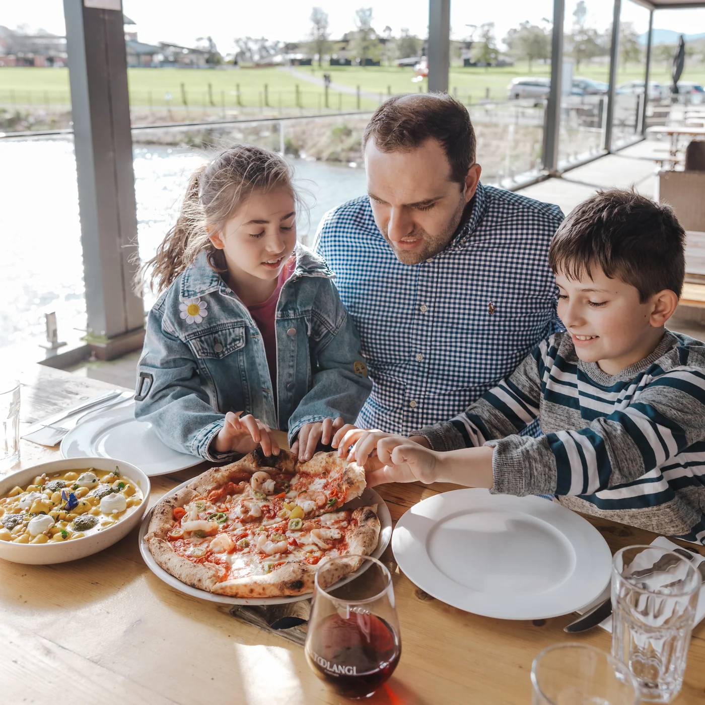 A parent and two children sharing pizza at Rochford